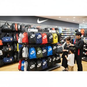 スポーツ用品店で多様な色とデザインのナイキナップサックが並べられた売り場の様子