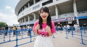 \<img src="h3\_venue.jpg" alt="ライブ会場のグッズ販売に並ぶミニスカ姿の女性"\>